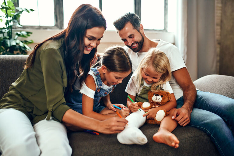 Family relaxing on the couch, signing the daughter's cast - Emac Air Conditioning